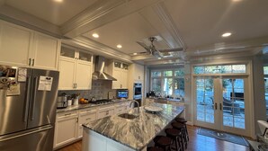 A modern kitchen with stainless steel appliances, a marble island, and a large window overlooking a garden. - Perfect location - renovated home w/2 master suites & exceptional outdoor space. (Washington)