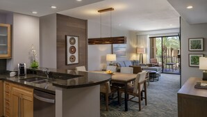 Une chambre d’hôtel moderne dotée d’un coin cuisine, d’un espace repas et d’un salon avec vue sur l’extérieur.