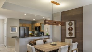Une cuisine moderne avec des meubles en bois, un réfrigérateur noir et un coin repas comprenant une table en bois et six chaises.