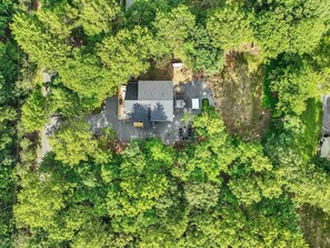 Eine Vogelperspektive eines Hauses, umgeben von üppigem Grün, mit einer gepflasterten Auffahrt und einer kleinen Terrasse.