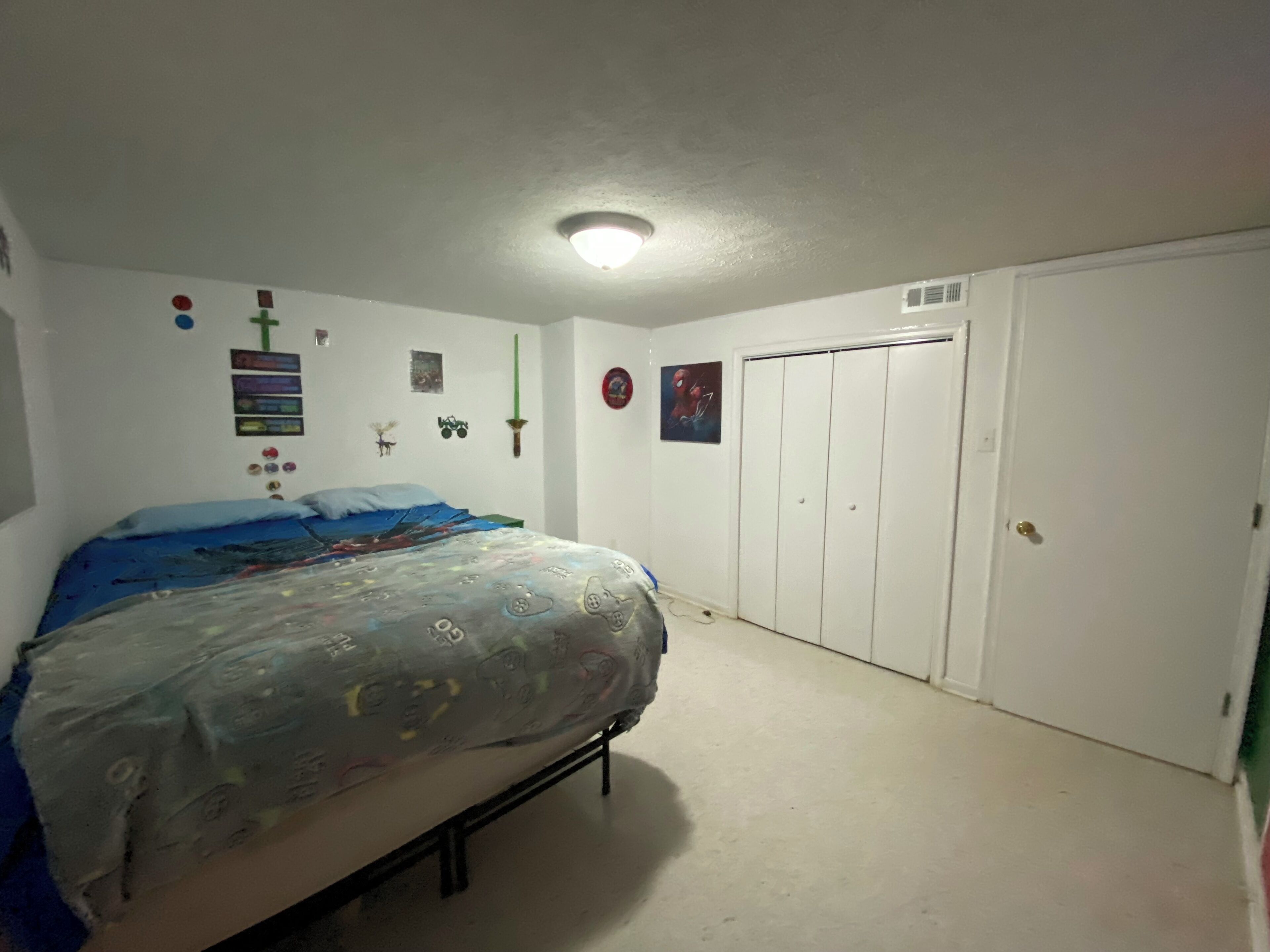 Een slaapkamer met een bed, een kledingkast en een plafondlamp.