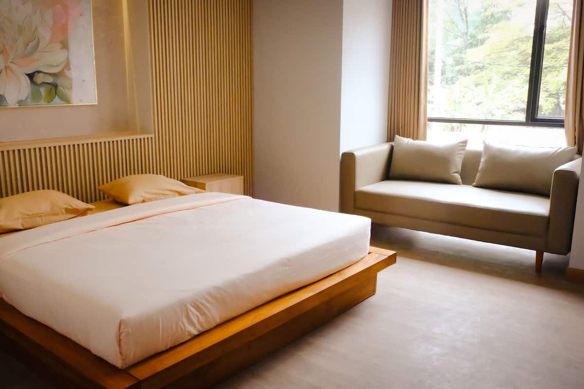 Une chambre moderne avec un grand lit, un canapé et une fenêtre avec des rideaux.