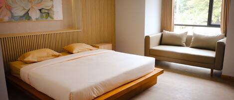 A modern bedroom with a large bed, a sofa, and a window with curtains.