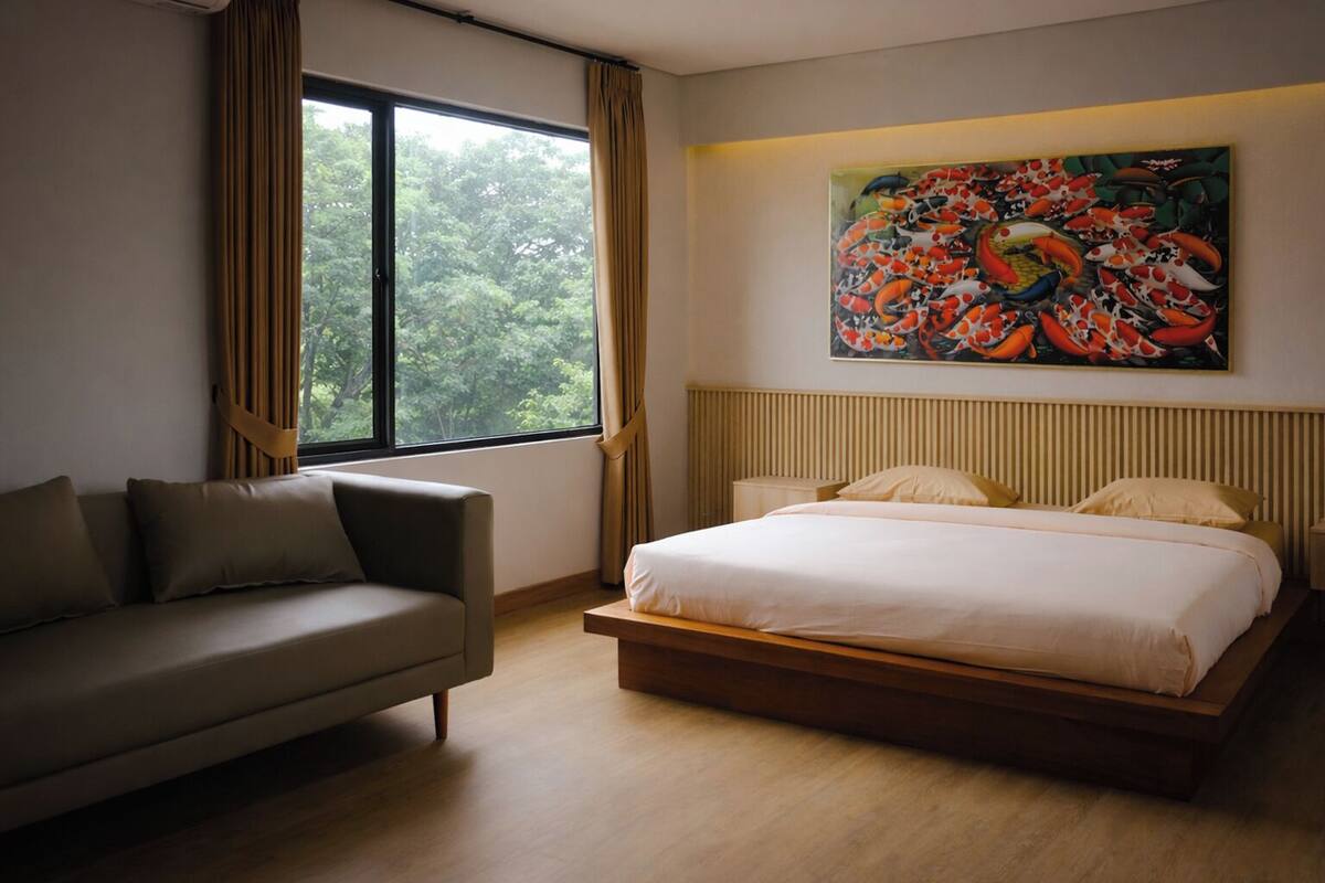 Une chambre d’hôtel moderne avec un grand lit, un canapé et un tableau représentant des poissons au mur.