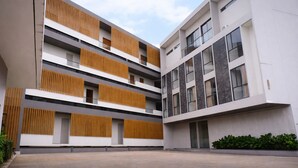 A modern multi-story building with a courtyard, featuring balconies with wooden slats and large windows. - Miracle Hotel Cianjur (Cianjur)