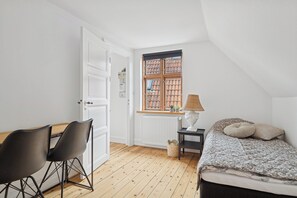 Ein Zimmer mit Bett, Schreibtisch mit Stühlen, einem Fenster mit Blick und einer Heizung.