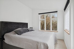 A bedroom with a bed, a window, and a view of trees.