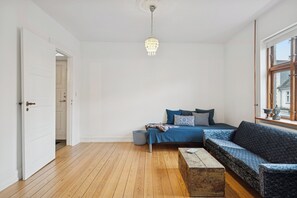 Ein Zimmer mit einem Bett, einem Schlafsofa, Holzboden, einer Chandelüster und einem Fenster.