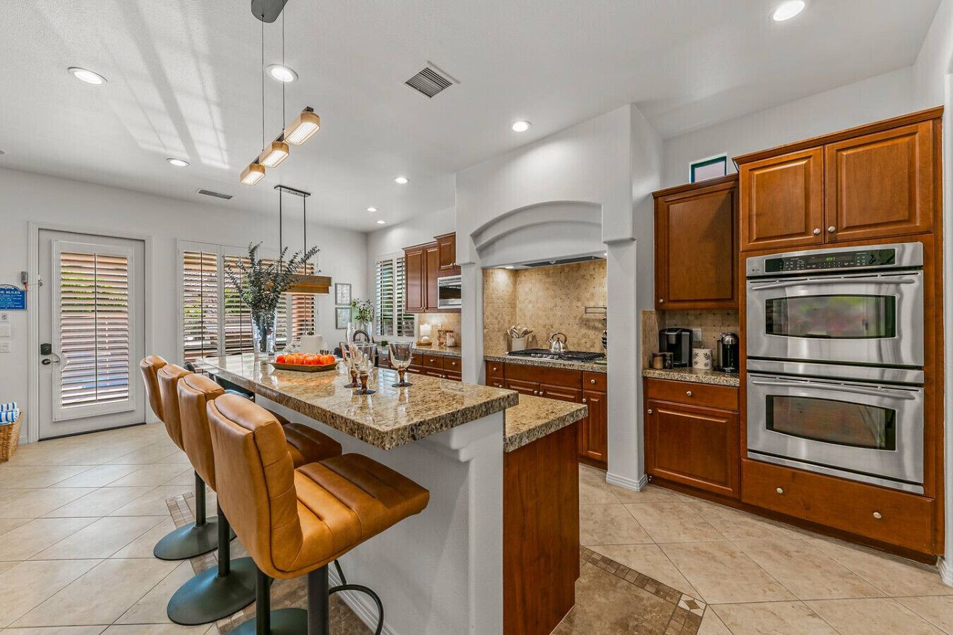 A modern kitchen with granite countertops, stainless steel appliances, and wooden cabinets.