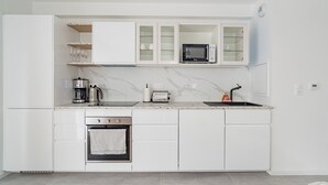 Eine moderne Küche mit weißen Schränken, einer eingebauten Mikrowelle, einem Toaster und einer Kaffeemaschine.