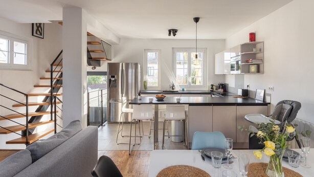 Een moderne keuken met een centraal eiland, barstoelen en een eettafel voor zes personen.