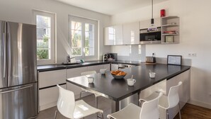 Een moderne keuken met een centraal eiland, witte kastjes en een roestvrijstalen koelkast.