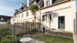 Een woongebouw met een tuin, een palmboom en een kleine tafel met stoelen.