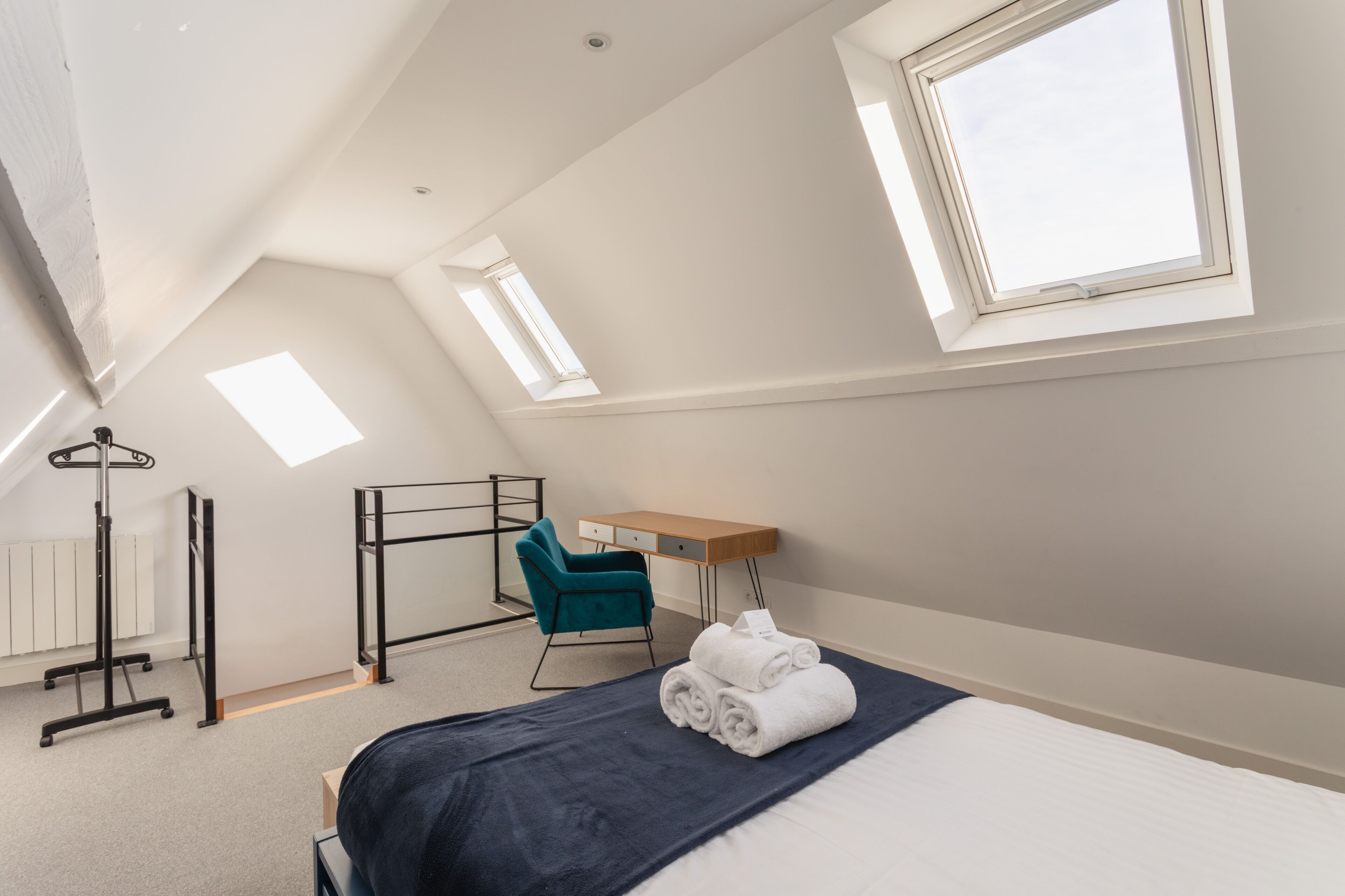 Une chambre à coucher avec un lit, un bureau, une chaise et une lucarne.