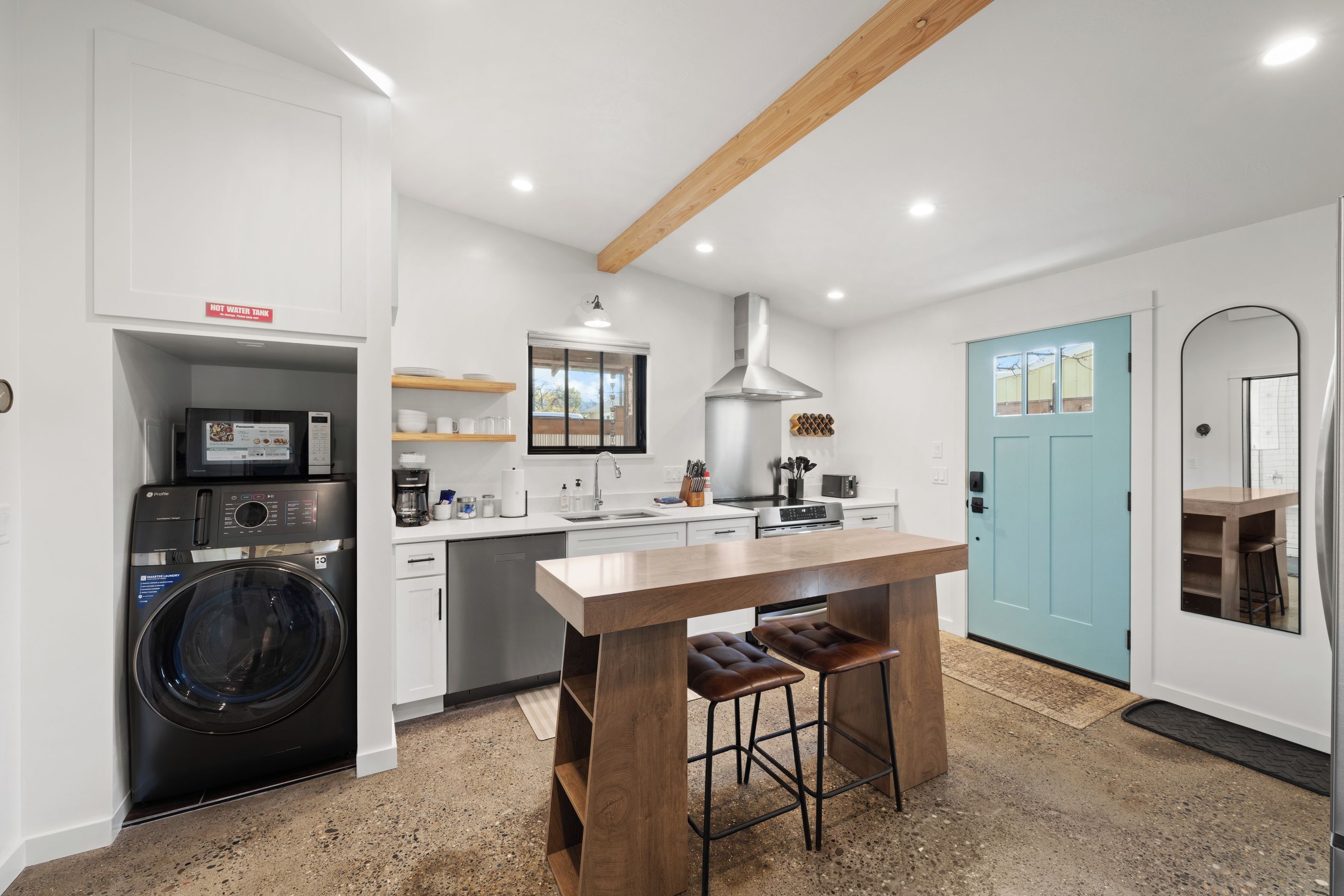 A modern kitchen with a built-in washer, a stainless steel range, and a blue door.