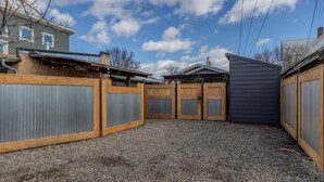 A fenced backyard with a gravel ground, wooden and metal fencing, and a grey building with a sloped roof. - 1 Bedroom Livingston Getaway (Livingston)