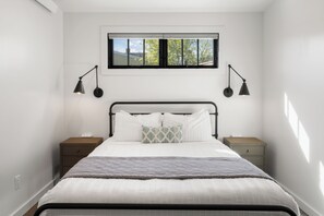 Een slaapkamer met een bed, twee nachtkastjes, een raam en twee wandlampen.