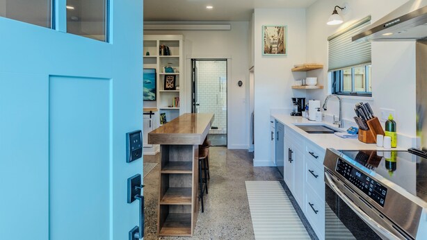 A modern kitchen with a wooden bar counter, stainless steel appliances, and white cabinetry. - 1 Bedroom Livingston Getaway (Livingston)