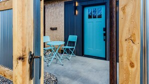An outdoor patio area with a blue door, a small round table, and two blue chairs. - 1 Bedroom Livingston Getaway (Livingston)