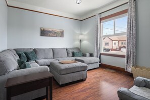 A modern living room with a grey sectional sofa, a small wooden coffee table, and a lamp.