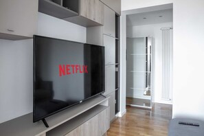 Ein modernes Wohnzimmer mit einem wandmontierten Flachbildfernseher, einer eingebauten Regaleinheit und einer Schiebetür zu einem weiteren Raum.