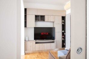 Un salon moderne avec un téléviseur à écran plat fixé sur un meuble en bois, une petite table blanche et un canapé.