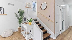 Eine Treppe mit hölzernem Geländer, einem weißen Konsolentisch und einer Topfpflanze.