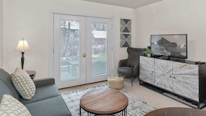 A modern living room with a sofa, armchair, coffee table, and a TV on a cabinet.