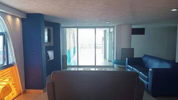 Een moderne woonkamer met een bank, een televisie en een groot raam.