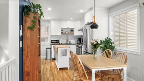 A modern kitchen with white cabinets, a wooden dining table, and a built-in oven.