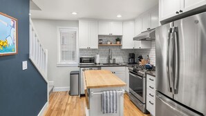 A modern kitchen with white cabinets, stainless steel appliances, and a wooden countertop.