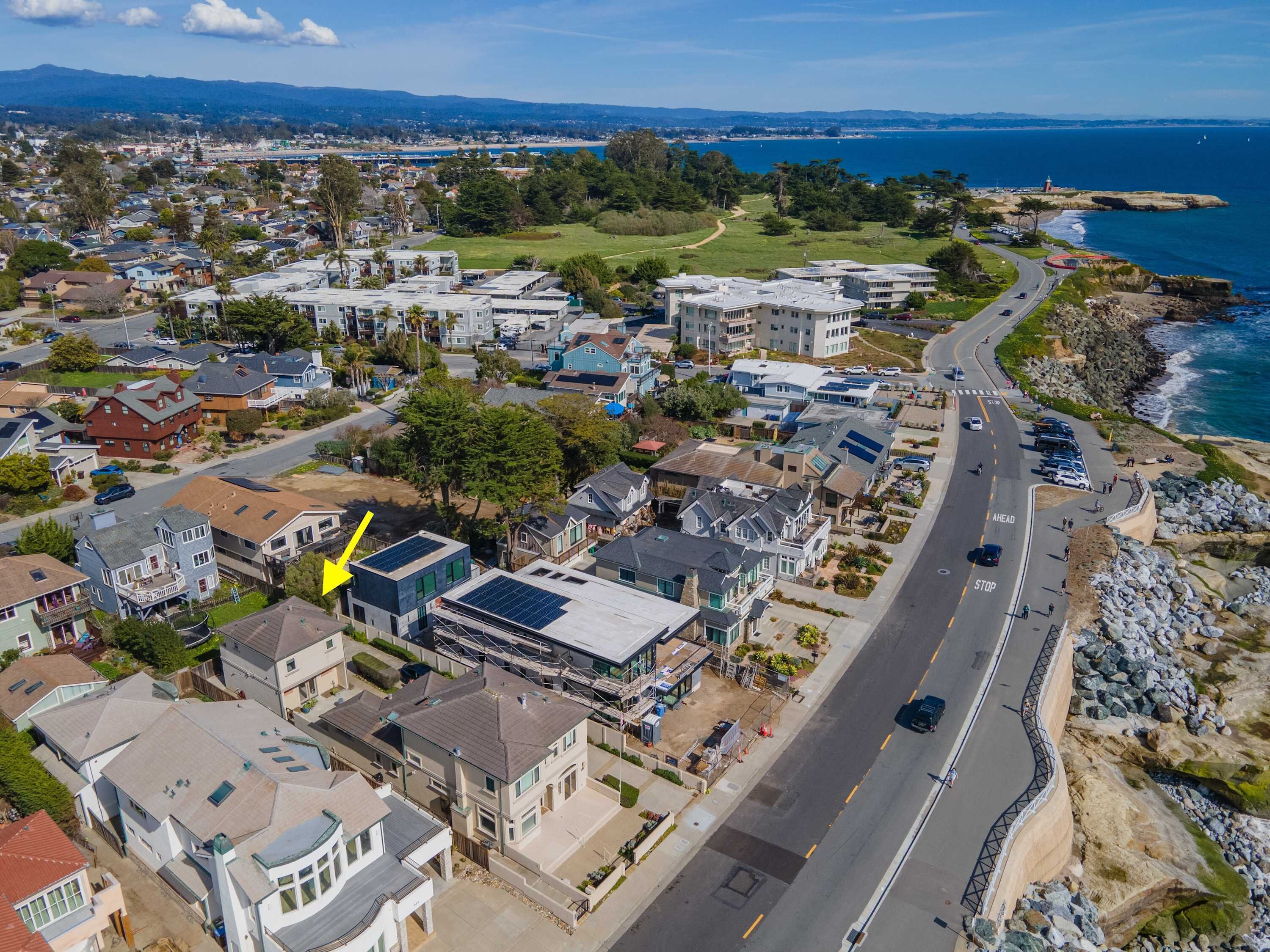 A coastal residential area with modern houses, a main road, and a view of the ocean.