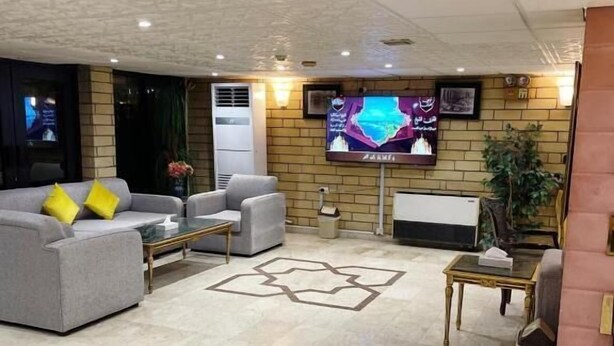 A modern living room with a grey sofa, a coffee table, and a TV mounted on the wall. - Rotana Furnished Apartments (Jeddah)