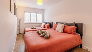 Un dormitorio con dos camas, una ventana con persianas, una lámpara de pie y una luz de techo.