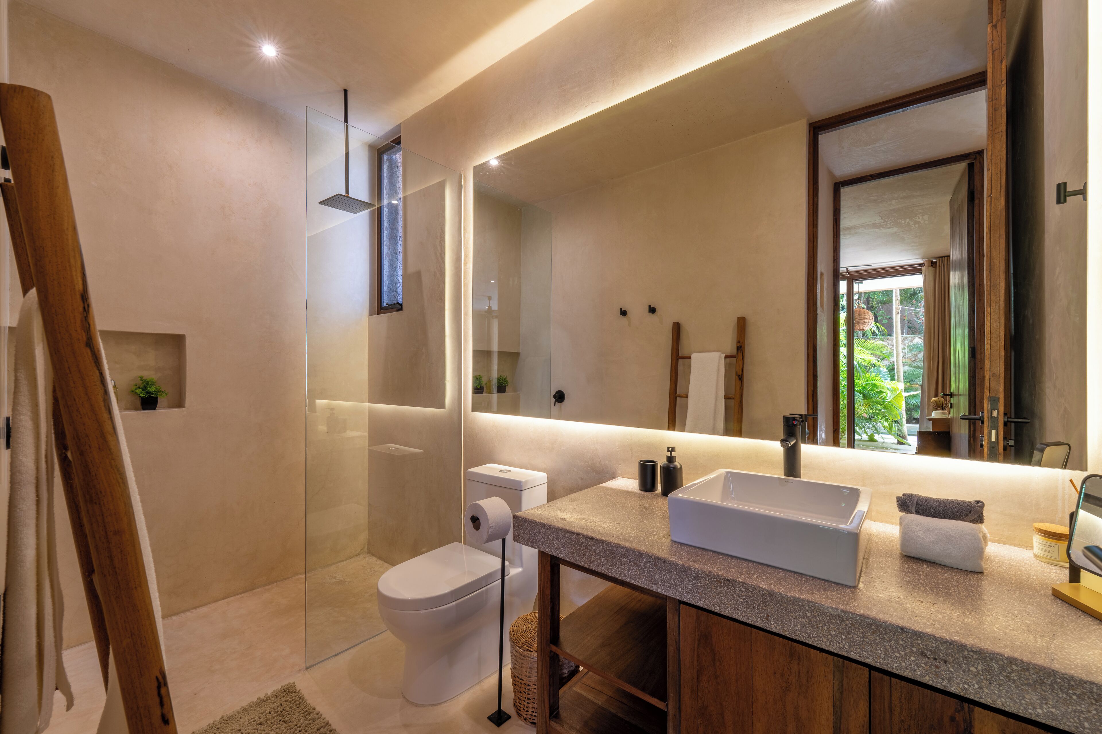 Een moderne badkamer met een glazen douchecabine, toilet, wastafel met grote spiegel en een houten kast.