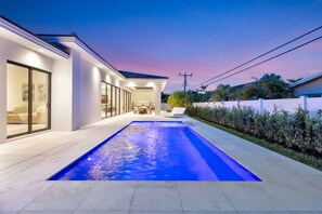 Ein modernes Haus mit Swimmingpool, großen Fenstern und einer Terrassenfläche.