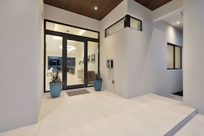 Ein modernes Interieur mit Glastür, Topfpflanzen und einem klaren, minimalistischen Design.