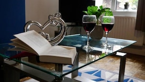 A glass table with a book, two wine glasses, and a heart-shaped metal decoration. - Ermine Road -  a house that sleeps 7 guests  in 4 bedrooms (Chester)
