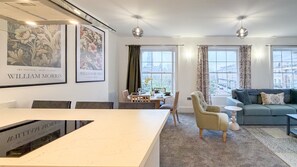 Un salon moderne avec un coin repas, de grandes fenêtres et des œuvres d’art accrochées aux murs.