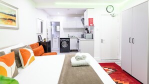 Ein Hotelzimmer mit einem Bett, einem Schlafsofa, einer Waschmaschine, einer Mikrowelle und einem Kleiderschrank.
