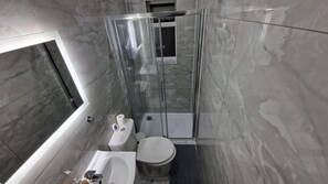 Un baño moderno con ducha envuelta en vidrio, inodoro blanco y bañera.
