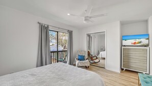 A bedroom with a large bed, a ceiling fan, a TV on a dresser, and a view of the outside balcony. - Prime Location/2 Bdr/Sleeps 7/Pet friendly (Santa Rosa Beach)