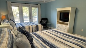 Un dormitorio con dos camas, un televisor, una silla y una mesita.