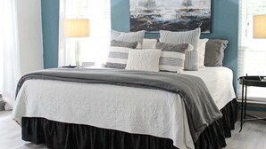 Een slaapkamer met een bed, een schilderij en een raam met gordijnen.