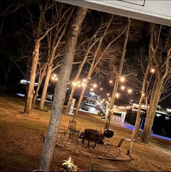 Un espacio al aire libre techado con luces colgantes, una mesa de comedor, sillas y un piano.