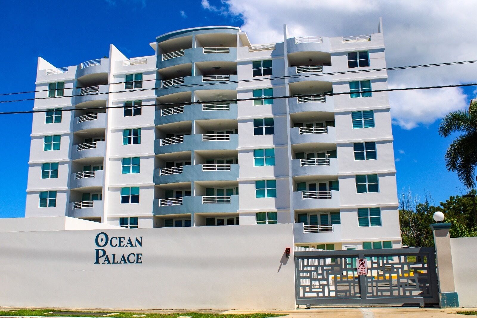 A multi-story hotel with balconies and a gated entrance.