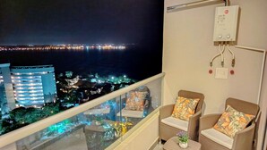 A balcony with wicker chairs and a small table, overlooking a cityscape at night. - Apartaloft Green Paradise - Santa Marina (Santa Marta)