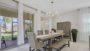 Un comedor con mesa de madera, sillas y una lámpara de araña.