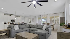 Una sala de estar moderna con un sofá modular, una mesa de centro de madera y un ventilador de techo.
