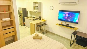 Une chambre d’hôtel équipée d’un lit, d’une télévision, d’une kitchenette et d’une armoire en bois.